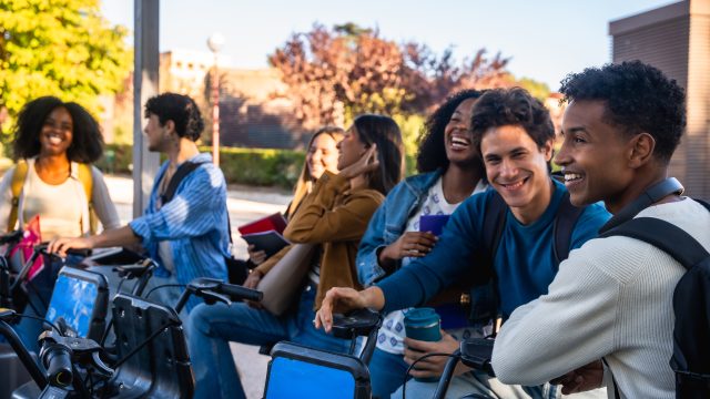 Diverse students smiling at bike sharing station on campus