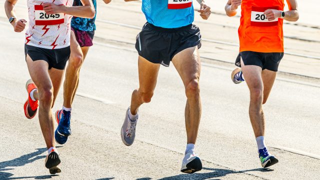 four athlete runners running marathon race in city road, numbers on shirts, summer sports games