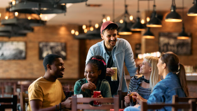 Group of happy friends talking while gathering in a pub.