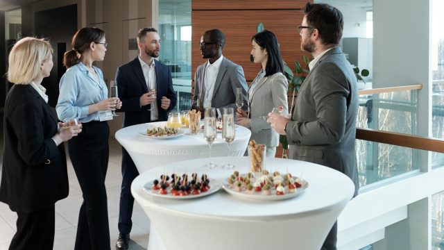 Group of intercultural business people looking at man with flute of champagne