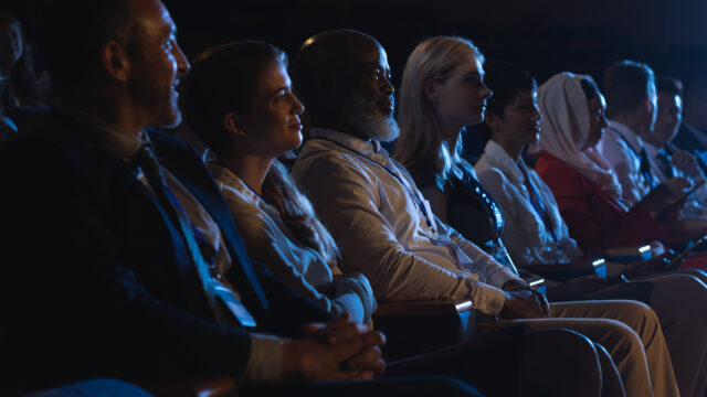 Side view of mixed race business colleagues sitting and watching presentation with audience