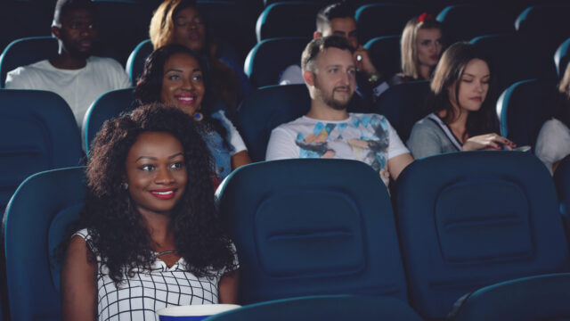 Smiling african woman spending free time in cinema.