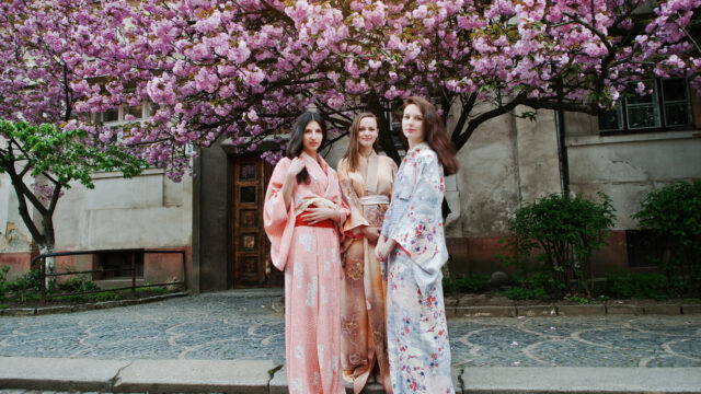 Three european girls wearing traditional japanese kimono backgro