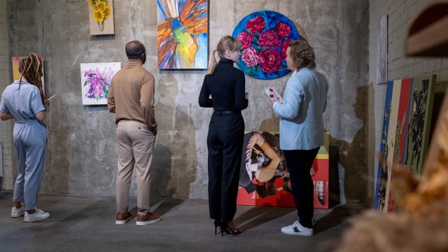Young blond woman talking to mature elegant man in art gallery